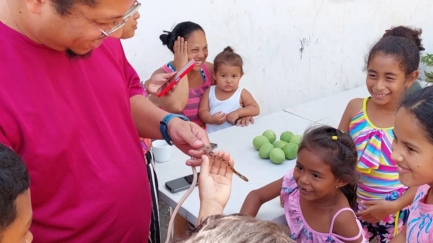Un educador de la fundación muestra una serpiente pequeña a un grupo de niñas y niños